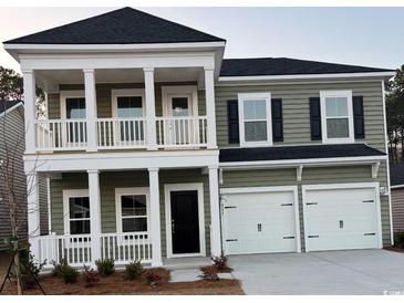 Two-story home with light green siding, double garage, and second floor porch at 2017 Lone Cypress Dr, Myrtle Beach, SC 29579