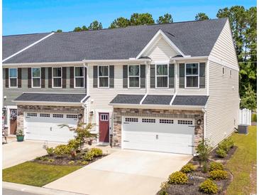 Charming townhome featuring stone accents, a one-car garage, and a neatly landscaped front yard at 308 Golan Circle # A, Myrtle Beach, SC 29579