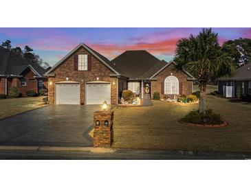 Charming brick home features a two-car garage, well-maintained lawn, and beautiful landscaping under a colorful sky at 387 Foxtail Dr., Longs, SC 29568