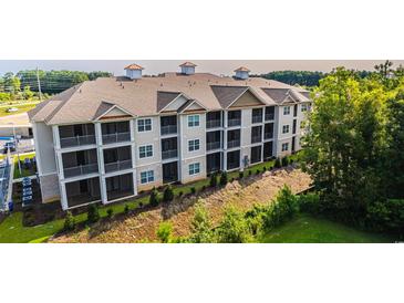 A modern, multi-story apartment building with screened-in porches, surrounded by trees at 395 S Crow Creek Dr. # 1704, Calabash, NC 28467