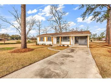 Charming one-story home featuring a brick exterior, mature trees, and a spacious front yard with a private driveway at 4320 Stevens St., Loris, SC 29569