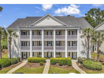 Charming condo building with white siding, multiple balconies, and lush landscaping at 4940 Windsor Green Way # 203, Myrtle Beach, SC 29579