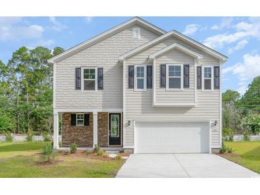 Charming two-story home with a stone-accented porch and a two-car garage, set against a backdrop of trees at 6031 Forest Dell Ct, Myrtle Beach, SC 29579