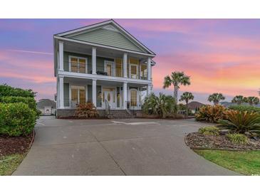 Two-story home with white columns, green siding, and lush landscaping provides tons of curb appeal at 898 Bluffview Dr., Myrtle Beach, SC 29579