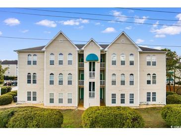 Three-story building featuring beautiful, neutral siding, blue awning, well-kept landscaping and numerous windows at 9750 Leyland Dr. # 2, Myrtle Beach, SC 29572