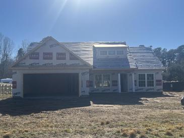 Unfinished home featuring a two-car garage and covered porch, awaiting personalization and finishing touches at 130 Palm Dr., Loris, SC 29569