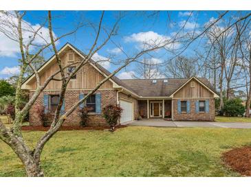 Charming brick home with blue shutters, manicured lawn, and a welcoming, attached two-car garage at 20 Brassie Dr., Carolina Shores, NC 28467