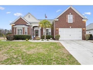 Charming brick home with a well-manicured lawn, palm tree, and attached two car garage at 320 Esher Ct., Myrtle Beach, SC 29579