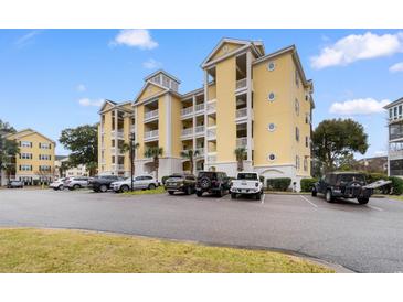 Low angle view of a yellow, multi-story condo building with a parking lot and neatly maintained landscaping at 601 N Hillside Dr. # 2331, North Myrtle Beach, SC 29582