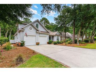 Charming home featuring an attached two-car garage and well-manicured front lawn with mature trees at 921 Heshbon Dr., North Myrtle Beach, SC 29582