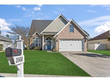 Charming brick home with a well-manicured lawn, blue front door, and two-car garage at 2668 Corn Pile Rd., Myrtle Beach, SC 29588