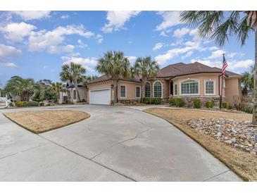 Elegant stucco home featuring palm trees, a circular driveway, and a two-car garage at 601 Tradewind Ct., North Myrtle Beach, SC 29582