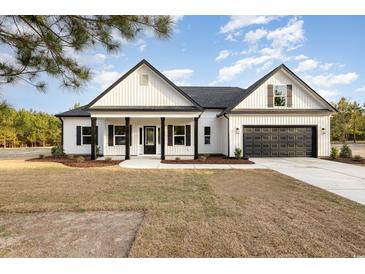 Charming white farmhouse with black accents, inviting front porch, and two-car garage at 1052 Merritt Rd, Conway, SC 29526