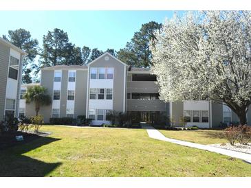 Three story condo building featuring a manicured lawn and mature trees at 140 Spanish Oak Ct. # 1, Surfside Beach, SC 29575