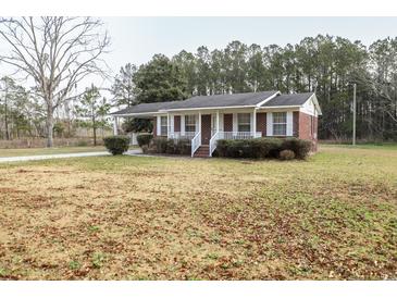 Cozy single-story brick home featuring a well-maintained front yard and covered porch at 3285 Della Rd., Longs, SC 29568