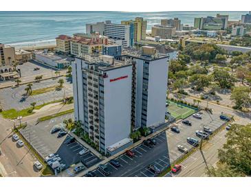 Stunning aerial view of Holiday Towers in Myrtle Beach, featuring parking, tennis court, and ocean views at 601 Mitchell Dr. # 203, Myrtle Beach, SC 29577