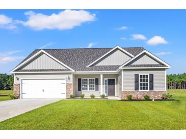 Charming single-story home boasts a two-car garage, well-manicured lawn, and neutral siding at 261 Six Mile Creek Dr., Georgetown, SC 29440