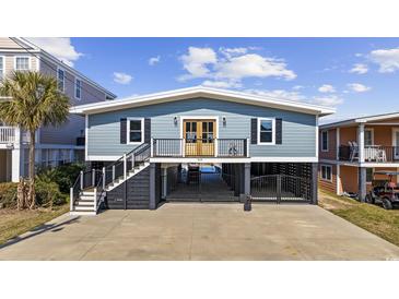 Charming coastal home with a blue exterior, black shutters, and a spacious drive-under garage at 414 S Dogwood Dr., Garden City Beach, SC 29576
