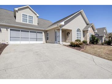Charming home featuring a two-car garage, stone accents, well-manicured landscaping, and neutral siding at 4243 Rivergate Ln., Little River, SC 29566