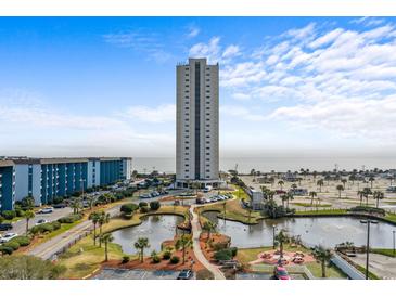 Scenic aerial view featuring a high-rise condo building, pond, parking, and partial ocean views on a partly cloudy day at 5905 S Kings Hwy. # 810-C, Myrtle Beach, SC 29575