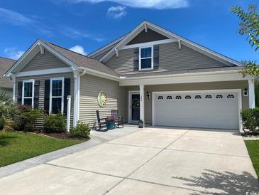 Charming home exterior with neutral siding, rocking chairs on the porch, and a two-car garage at 808 Yauhannah Dr., Little River, SC 29566