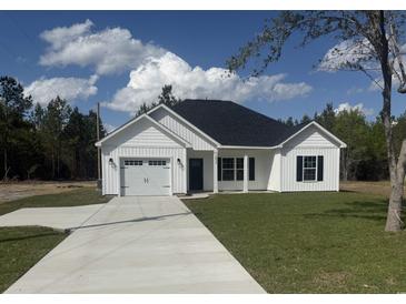 Charming single-story home with a well-manicured lawn, concrete driveway and a classic black and white color scheme at 10534 W Highway 19, Loris, SC 29569