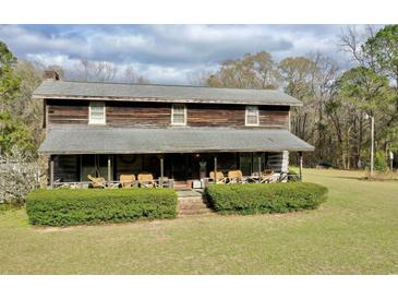 Rustic two-story home featuring a full front porch and lush green lawn at 1993 Meadowood Ln., Longs, SC 29568