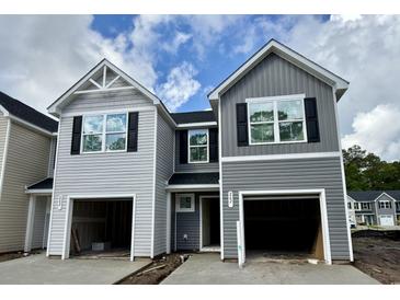 New townhomes with attached garages featuring gray siding and black shutters under a blue sky at 262 Christiana Ln. # B, Myrtle Beach, SC 29579