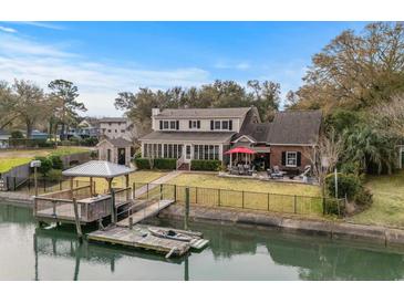 Stunning waterfront home featuring a private dock, manicured lawn, and outdoor seating area at 288 Rum Gully Rd., Murrells Inlet, SC 29576