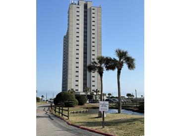 Towering condo building with well-maintained landscaping and palms under a bright blue sky at 5905 South Kings Hwy. # 1116, Myrtle Beach, SC 29575