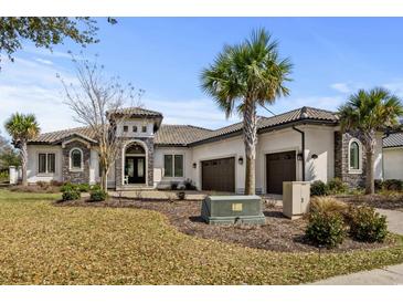 Elegant stucco home with a tile roof, stone accents, and a well-manicured front yard at 1549 Casita Ln., Myrtle Beach, SC 29579