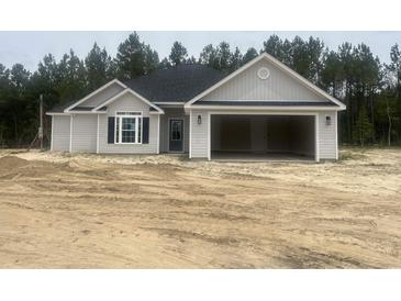 Charming single-story home with gray siding and a spacious two-car garage, set against a backdrop of lush trees at 2921 Hughes Gasque Rd., Aynor, SC 29511