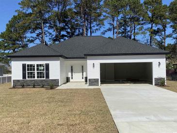 Charming home with black shutters, a grey roof, an open two-car garage and a well-manicured lawn at 311 St. Andrews Ln., Myrtle Beach, SC 29588