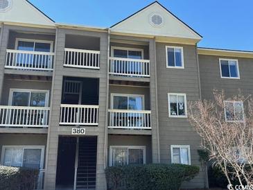 Three-story condo building with balconies and neutral siding on a sunny day at 380-K Myrtle Greens Dr. # 380-K, Conway, SC 29526
