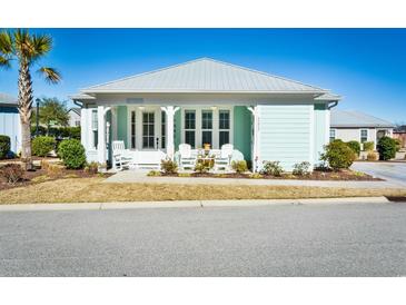 Charming beach house with a covered porch, white Adirondack chairs, and a vibrant turquoise exterior at 5223 Sea Coral Way, North Myrtle Beach, SC 29582