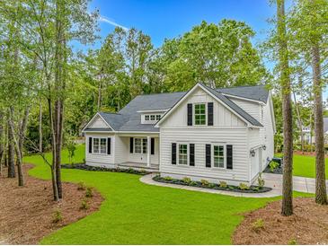 Beautiful white home featuring black shutters, complemented by a lush green lawn and mature trees at 19 Coventry Pl., Pawleys Island, SC 29585