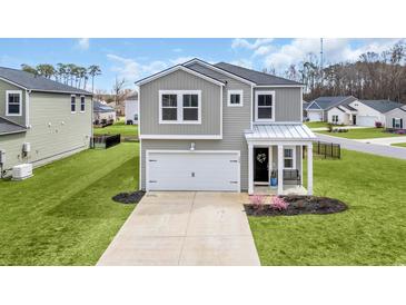 Charming two-story home with grey siding, white trim, two car garage, and manicured lawn at 204 Leaflet Loop, Pawleys Island, SC 29585