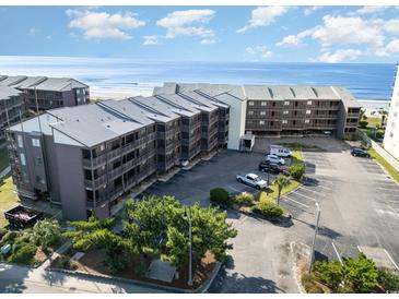 Coastal condo complex with a shared parking lot and ocean views under a sunny sky at 108 Ocean Blvd. N # 101, North Myrtle Beach, SC 29582