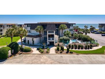 Exterior view of a condo building with pool and palm trees near the ocean at 5601 N Ocean Blvd. # C-311, Myrtle Beach, SC 29577