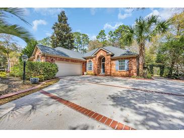 Charming brick home featuring a spacious driveway, blue shutters, and well-manicured landscaping at 74 Dornoch Dr., Pawleys Island, SC 29585
