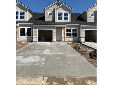 Newly constructed townhouse featuring a concrete driveway, attached garages and light beige siding at 2038 Wild Indigo Circle Nw # 205, Calabash, NC 28467
