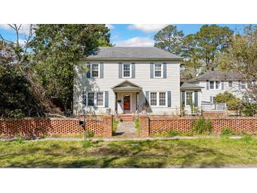 Charming two-story home with blue shutters and a brick fence at 103 N Magnolia Ave., Andrews, SC 29510