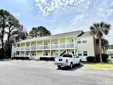 Exterior view of a two-story condominium building with white balconies and ample parking at 4150 Horseshoe Rd. N # 8, Little River, SC 29566