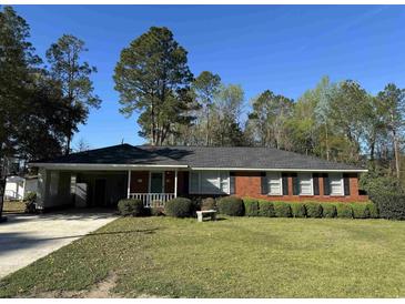 Charming brick ranch-style home with a well-manicured lawn and mature trees in a quiet neighborhood at 61 Lakewood Dr., Andrews, SC 29510