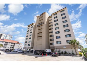 Exterior daytime view of condominium building with parking lot and beautiful blue sky at 707 S Ocean Blvd. # 602, North Myrtle Beach, SC 29582