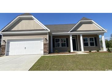 Charming single-story home featuring a two-car garage, covered entry, and manicured lawn at 997 Oak Hollow St., Longs, SC 29568