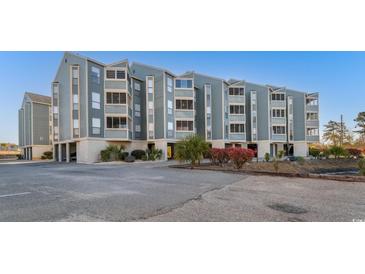 Three-story condo building with blue siding and neatly maintained landscaping at 1101 Possum Trot Rd. # C-303, North Myrtle Beach, SC 29582