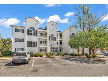 Attractive three-story condo building with white siding and well-maintained landscaping and ample parking space at 1505 Lanterns Rest Rd. # 101, Myrtle Beach, SC 29579
