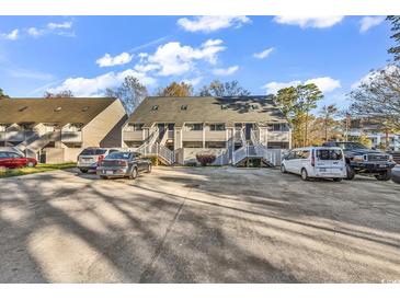 Exterior shot of a two-story townhome with outside staircase, asphalt parking lot, and blue skies at 400 Cambridge Circle # L-7, Murrells Inlet, SC 29576
