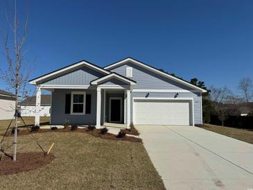 Charming single-story home featuring light blue siding, a two-car garage, and a well-manicured front yard at 5011 Neverland Ct, Myrtle Beach, SC 29588